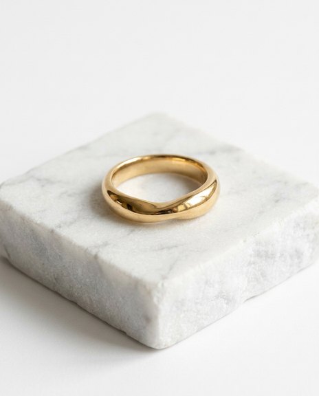 Sculptural gold band on a white stone plinth