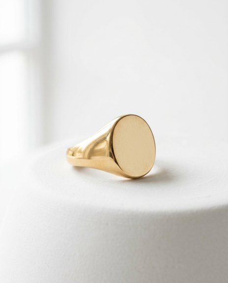 Minimal gold signet ring photographed on white ceramic