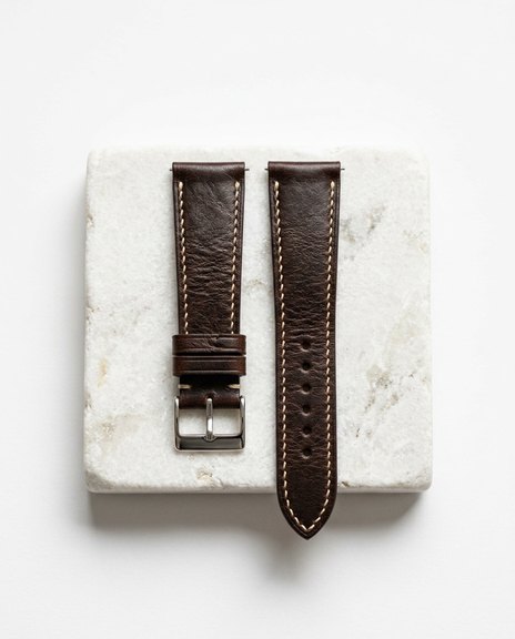 Pair of espresso leather watch straps arranged on white stone